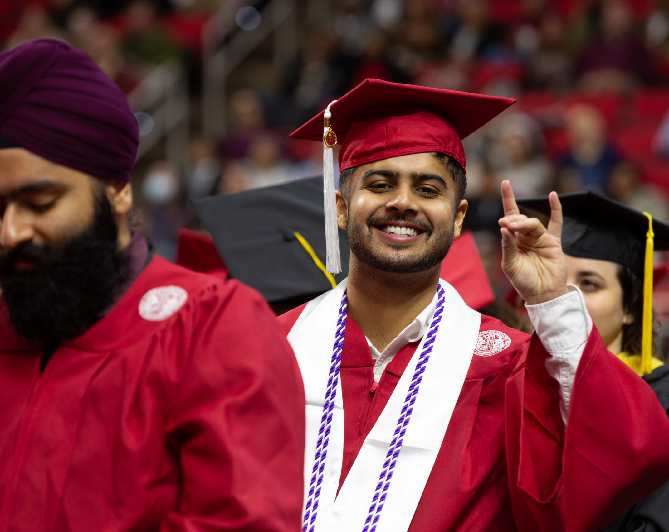 Undergraduate makes wolf hand sign at Fall 2022 Commencement.
