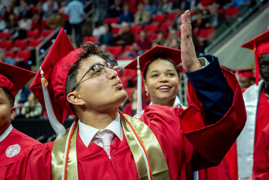 NC State graduate blows a kiss to guests in attendance at the Fall 2023 ceremony in PNC Arena.