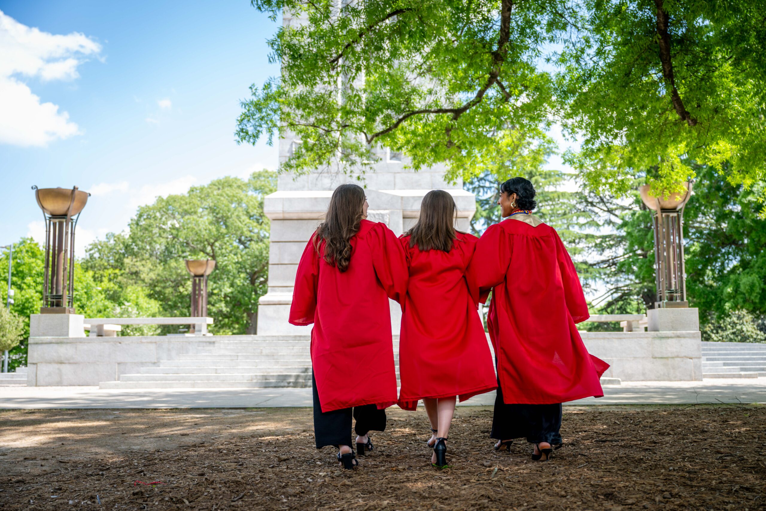 Students in regalia meet at the Memorial Belltower to celebrate graduation.