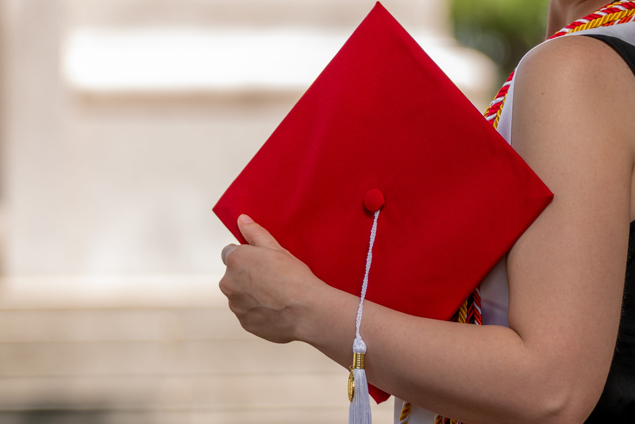 Student holds a graduation cap at the Memorial Belltower.